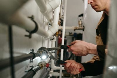 Technician inspecting commercial plumbing pipes in Fremont