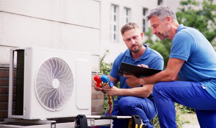 HVAC technicians installing an outdoor air conditioning unit in Fremont
