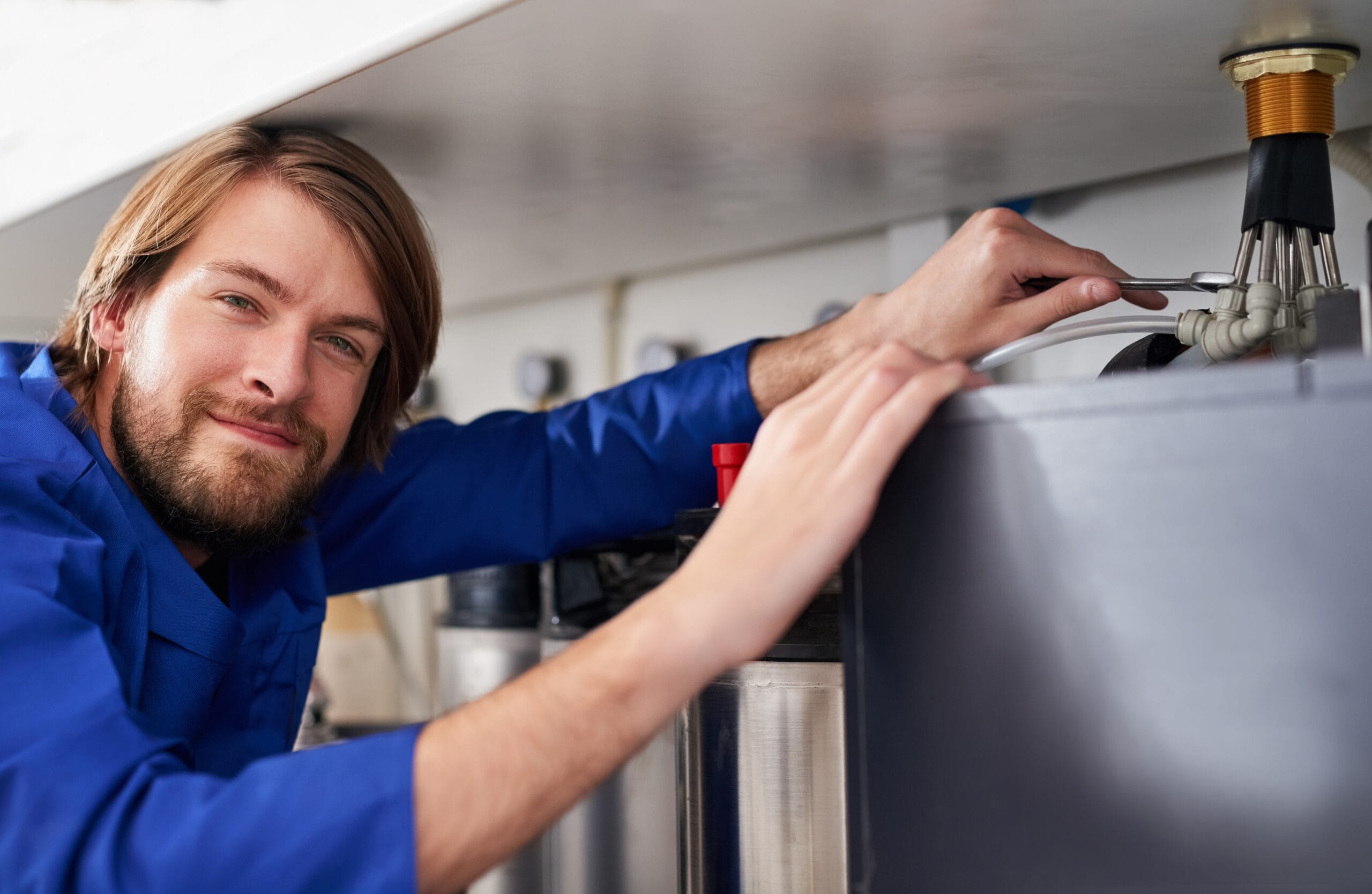 Technician servicing a residential water heater tank in Fremont